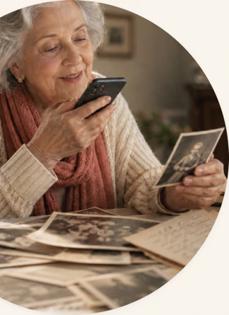 An older woman records a memory into her phone, surrounded by printed photographs