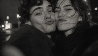 A couple pressed cheek to cheek on a city street at night