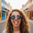 Mary, grinning in sunglasses on a brightly painted street